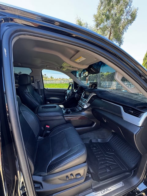 Interior of a blue pickup truck with black leather seats, steering wheel, dashboard, and windshield view of outdoor scenery