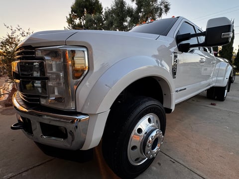 White Ford F-Series pickup truck with towing capability parked at sunset, rear view showing dual rear wheels and open door