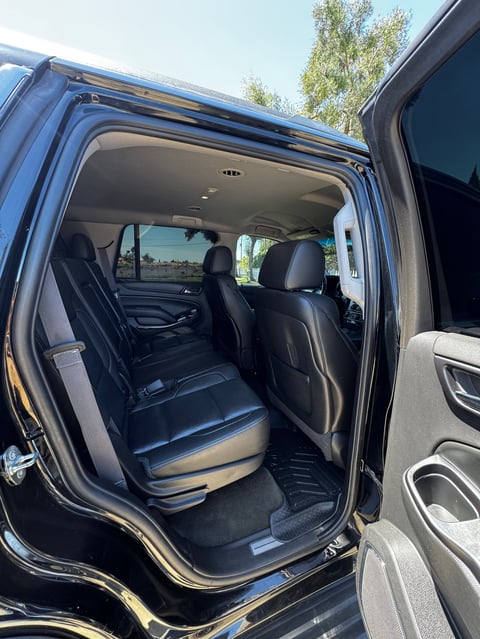 Interior view of a blue SUV with open rear door showing black leather seats and spacious cabin