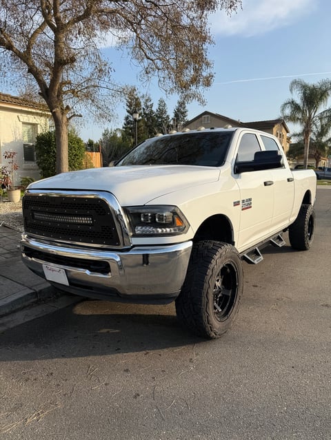 White Dodge Ram pickup truck parked on residential street with trees and houses in background